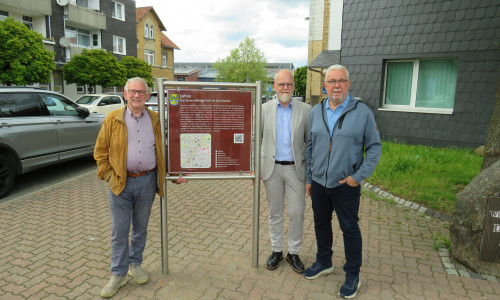 Ortsheimatpfleger Wilhelm Knigge, Verwaltungsleitung Tobias Breske und Ortsbürgermeister Heinrich Köther mit der neuen Infotafel auf dem Marktplatz.