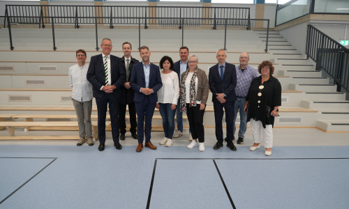 Vertreterinnen und Vertreter aus Verwaltung, Schule und Wolfsburger Schulmodernisierungsgesellschaft bei der Wiedereröffnung der sanierten Dreifeldsporthalle am Schulzentrum Vorsfelde. Mit dabei waren unter anderem Oberbürgermeister Dennis Weilmann (4. v. l.), Stadträtin Iris Bothe (4. v. r.), die Geschäftsführer der Wolfsburger Schulmodernisierungsgesellschaft Christoph Andacht und Marc-Frederik Augath sowie die Schulleitungen des Schulzentrums.