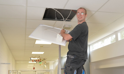 Ein Mitarbeiter des Bauwirtschaftshofs der Gemeinde Ilsede nimmt den Einbau der Beleuchtung in der Grundschule vor.