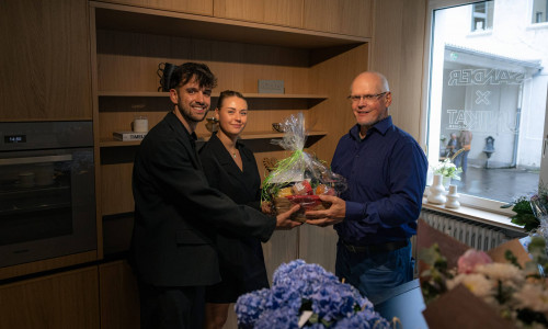 Die Gründer Tim Deichmann und Sina Joost erhalten ein Einzugsgeschenk von Rainer Müller, der bei Garant Gründungen betreut.
