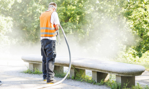 Eine Parkbank wird sandgestrahlt.