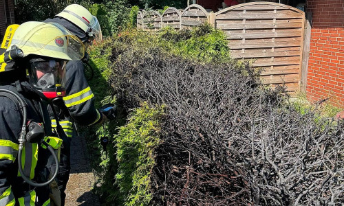 Atemschutzgeräteträger der Feuerwehr Haxtum kontrollierten die bereits durch Anwohner erfolgreich gelöschte Hecke nach.  (Archiv)