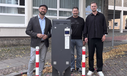 Bürgermeister Malte Schneider, Kai Engel und Lukas Grebener, Wirelane GmbH, präsentieren den Ladepunkt am Neuen Rathaus.