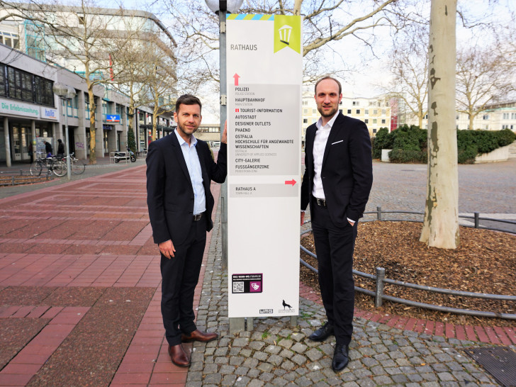 Die WMG-Geschäftsführer Jens Hofschröer (rechts) und Dennis Weilmann an einer Stele vor dem Wolfsburger Rathaus. Foto: WMG