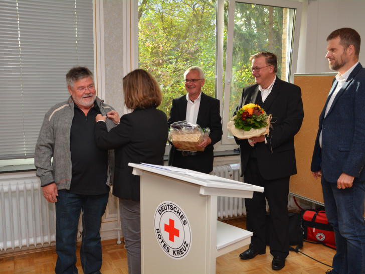Heike Kanter steckt Achim Liersch die Ehrennadel an. Daneben freuen sich Horst Kiehne, Andreas Ring und Axel Szybay. Foto: DRK