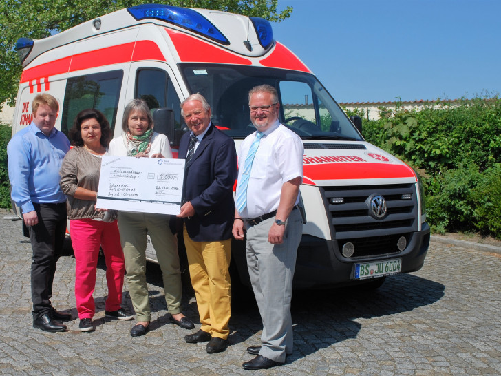 Walter Dieckmann übergibt den symbolischen Spendenscheck an Gudula von Kalm von den Johannitern. Links davon Marc Wegner von den Johannitern und Walter Dieckmanns Frau Anne. Rechts steht Johanniter-Regionalvorstand Hans Joachim Halbach. Foto: Lena Kopetz / Johanniter