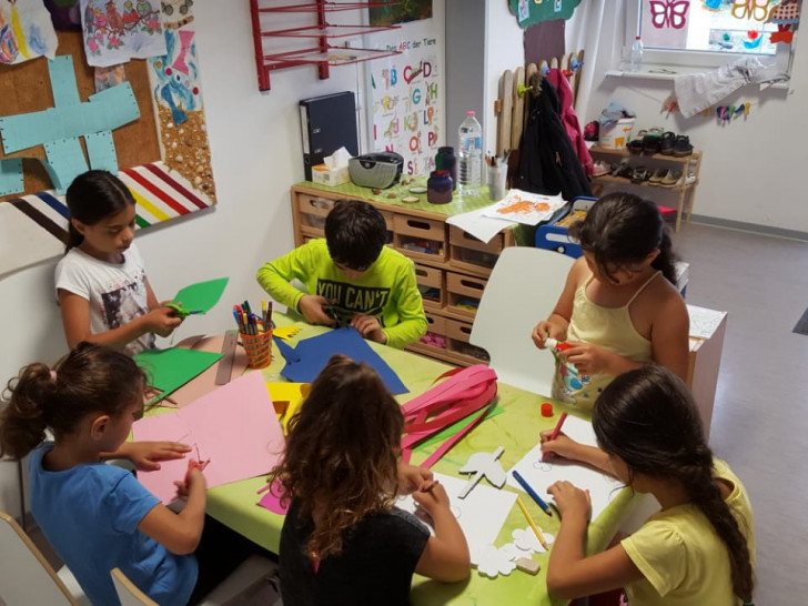 Die Kinder der Familien vom Schützenplatz basteln im Kinderraum der Wohnanlage schon voller Vorfreude bunte Dekoration für das Sommerfest. Foto: Stadt Wolfenbüttel
