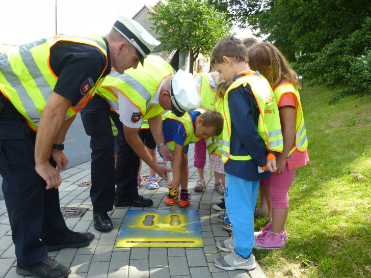 Gunter Pramann (hinten) und Ralf Buchmeier unterstützen die Kinder beim Aufsprühen der gelben Füße. 
Foto: Timo Pischke\DRK Kreisverband Goslar