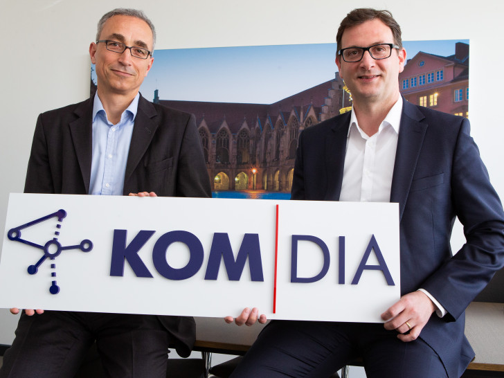 Dr. Volker Lang, Vorstand BS Energy und Geschäftsführer Kom-Dia, (links) und Julien Mounier, Vorstandsvorsitzender BS Energy, (rechts) mit dem Kom-Dia-Logo. Foto: BS Energy/Florian Kleinschmidt. 