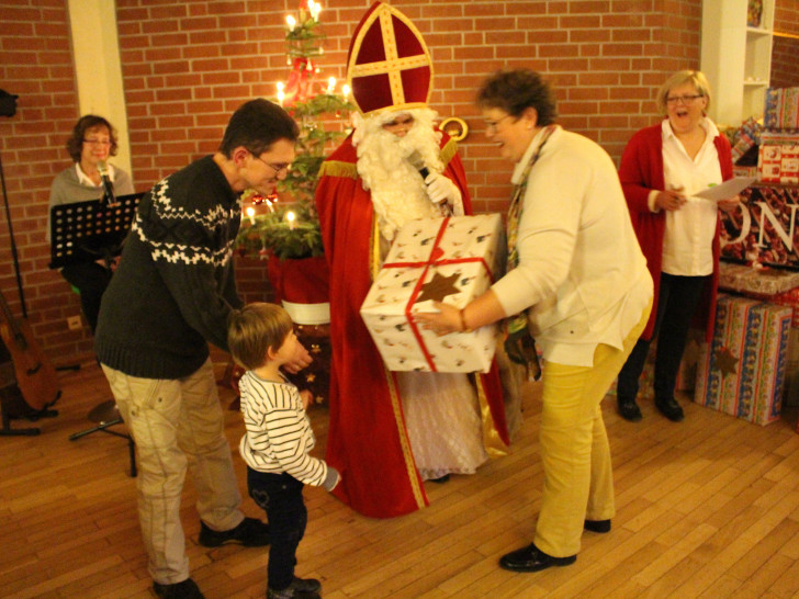 Die vierjährige Lisa-Marie nimmt mit Hilfe ihres Papas ein großes Paket vom Weihnachtsmann und seinen Helferinnen entgegen. Fotos: Alexander Dontscheff
