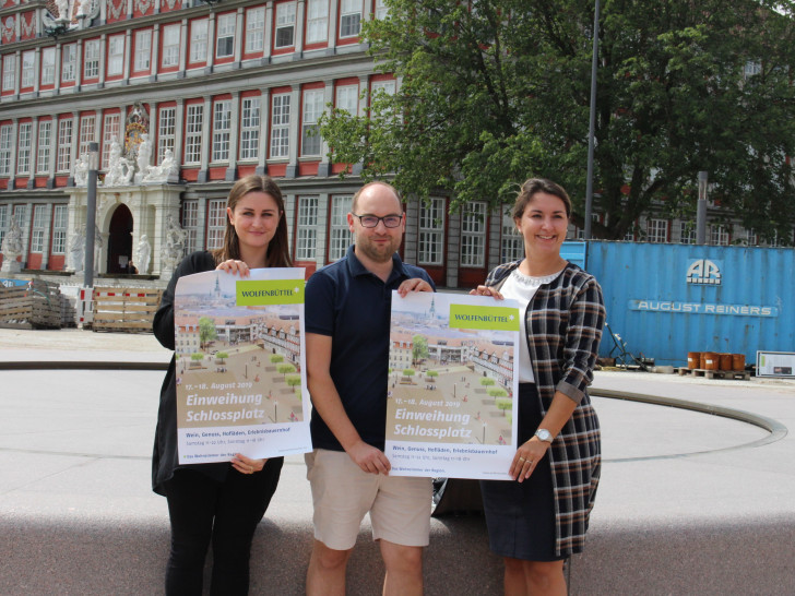 Vivien Strümpfler, Sebastian Kirchner und Anna Wohlert-Boortz präsentieren das Plakat zur Schlossplatzeinweihung vor dem neuen Brunnen. Foto: Marvin König
