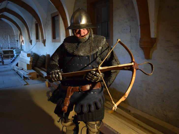 Restaurator Jens Klocke führt in der stilechten Kleidung eines mittelalterlichen Armbrustschützen vor, wie eine solche Waffe funktionierte. Foto: Stadt Goslar
