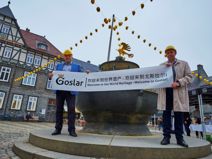 Mathias Derlin (Geschäftsführer GOSLAR marketing gmbh) und Gerhard Lenz (Geschäftsführer Weltkulturerbe Erzbergwerk Rammelsberg Goslar GmbH und Direktor der Stiftung Welterbe im Harz) heißen die Besucher auf Mandarin und Englisch auf dem Goslarer Marktplatz willkommen. Quelle: GOSLAR marketing gmbh/Fotograf Stefan Sobotta