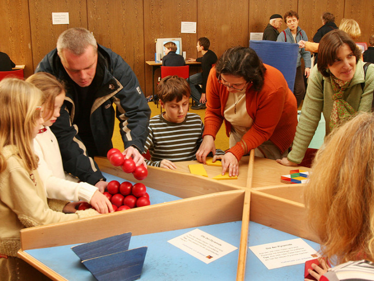 Kinder und ihre Eltern probieren sich am sogenannten Knobeltisch aus. Foto: Veranstalter