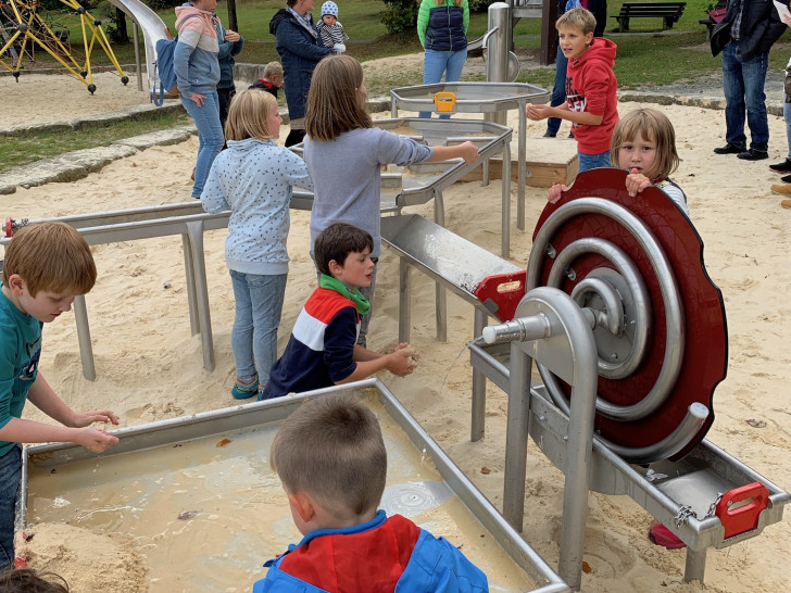 Wasser und Sand: Kinder weihen die neue Matschanlage im Kurpark offiziell ein, während Karin Jünke, Heinrich Wilgenbus und Dr. Oliver Junk das Treiben beobachten. Foto: Stadt Goslar
