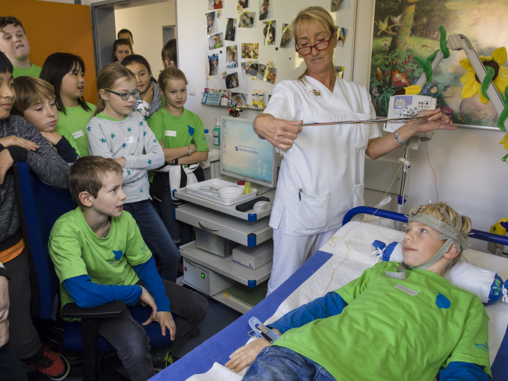 Gesundheits- und Kinderkrankenpflegerin Astrid Rabe zeigte den Kiwi-Forschern, wie man mit einer „Igelmütze“ Gehirnströme misst. Foto: Peter Sierigk/Klinikum Braunschweig