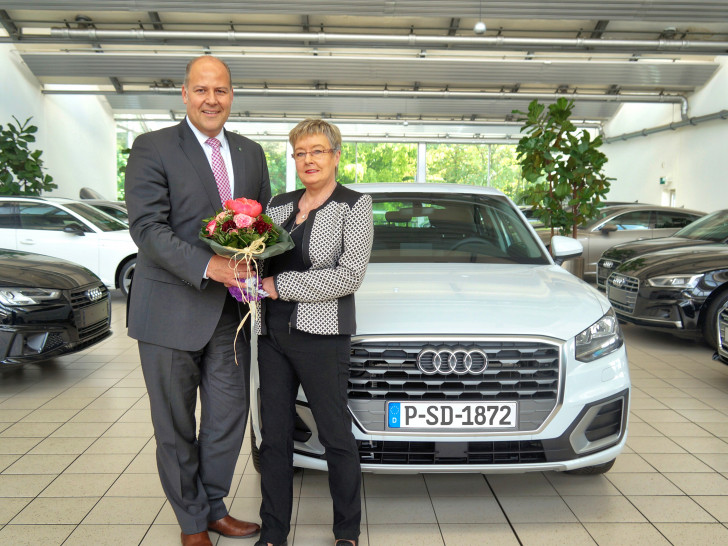 Carsten Graf, Vorstandssprecher der PSD Bank Braunschweig eG, und Gewinnerin Kristina Meyer posieren vor dem gewonnenen Audi Q2. Foto: Markus Siemens, PSD Bank