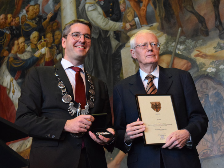 Dr. Oliver Junk und Kay Nehm zeigen auf der Bühne in der Kaiserpfalz Urkunde und Ehrenplakette, die die Stadt Goslar dem langjährigen VGT-Präsidenten verliehen hat. Foto: Stadt Goslar