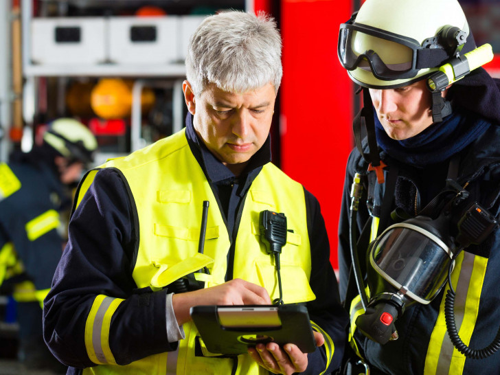 Zwei Feuerwehrmänner schauen auf ein Tablet. Symbolfoto: Agentur für Arbeit