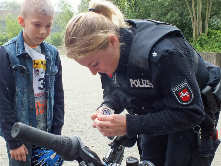 Eine Polizeikommissarin versieht das Rad eines Schülers des Gymnasiums Julianum mit einer ADAC Prüfplakette. Foto: Kreisverkehrswacht Helmstedt e.V.
