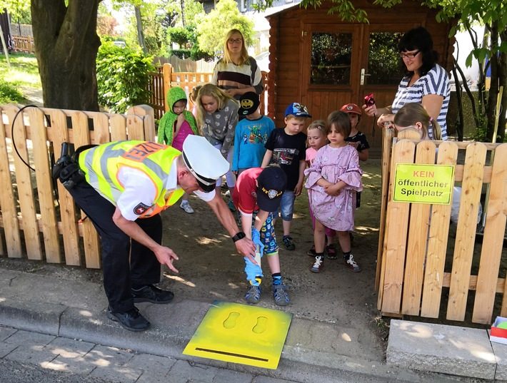Polizeikommissar Ralf Buchmeier (Verkehrssicherheitsberater der PI Goslar) sprüht zusammen mit den Kindern die "Gelben Füße". Foto: Polizei Goslar