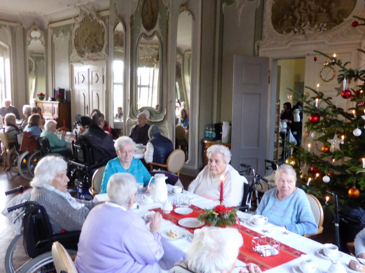 Die Vertreterinnen der Frauenhilfe mit den Bewohnern im adventlich geschmückten Spiegelsaal der Seniorenbetreuung Schloß Schliestedt. Foto: Seniorenbetreuung Schloß Schliestedt