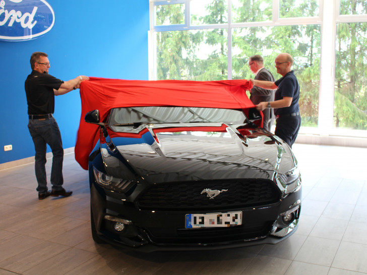 Käufer Ralf Richter, Ford-Werke Gebietsleiter Karsten Maifeld und Stefan Piske decken den neuen Mustang ab. Foto: Jan Borner