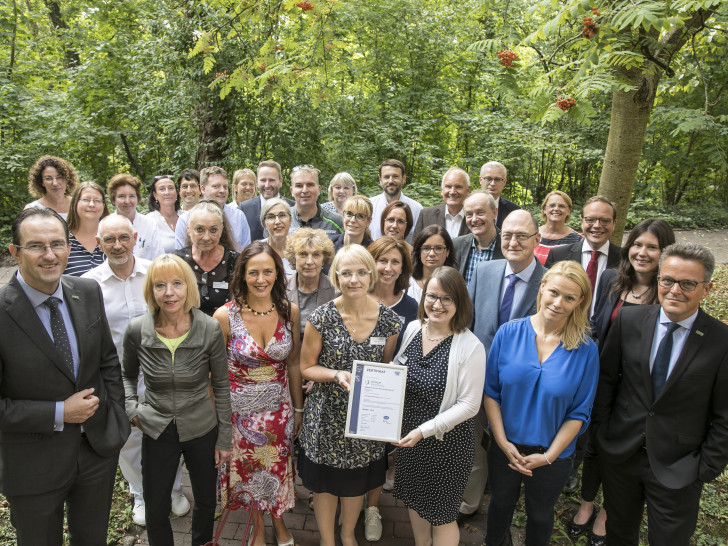 Klinikum-Geschäftsführer Dr. Andreas Goepfert (links) präsentiert gemeinsam mit am Audit beteiligten Mitarbeiterinnen und Mitarbeitern das Zertifikat gemäß DIN EN ISO 9001:2015. Foto: Klinikum Braunschweig / Peter Sierigk