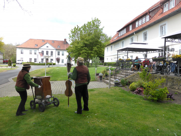 Die Drehorgelspieler vor dem Langhaus zur Freude der Bewohner. Im Hintergrund der Maibaum mit wehenden bunten Bändern vor dem Schlossportal.