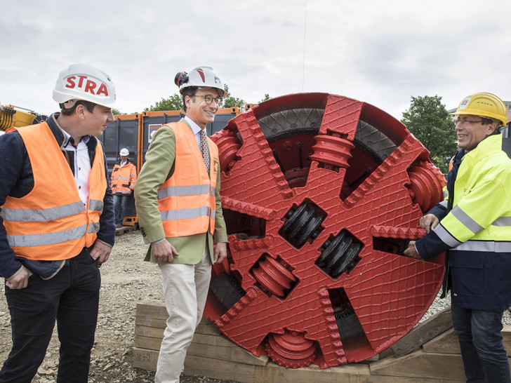 Maik Eggert (Gruppenleiter, Strabag AG), Florian Kroker (Gesellschafter, Max Kroker Bauunternehmung GmbH & Co.) und Andreas Hartmann (Geschäftsführer, Stadtentwässerung Braunschweig GmbH) sehen sich den Bohrkopf der Tunnelbohrmaschine aus der Nähe an.
