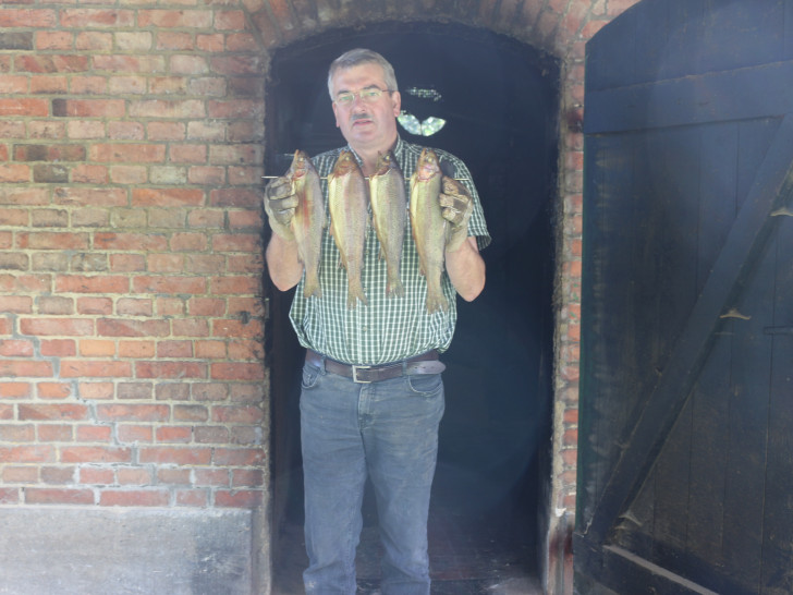 Klaus Lübbe holt geräucherte Fische aus dem Ofen. Alle Fische, die Lübbe verkauft, kommen aus den eigenen Teichen.