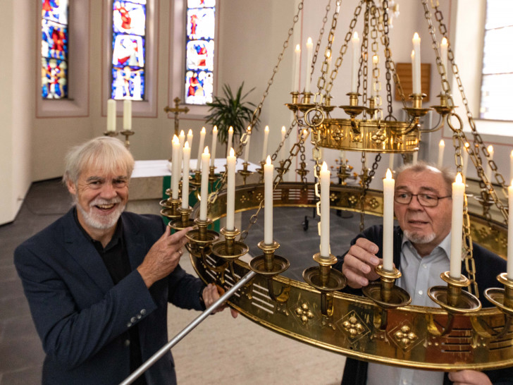 Pastor Uwe Teichmann und Elektromeister Herbert Lindhofer mit dem alten Kronleuchter in der Kirche. 