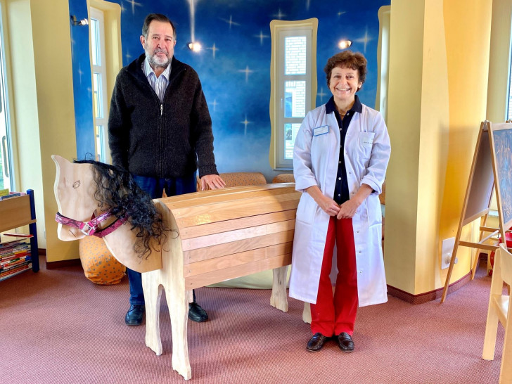 Gerhard Kupka (li.) übergibt sein selbst gebautes Holzpferd an Chefärztin Prof. Dr. Jacqueline Bauer. 