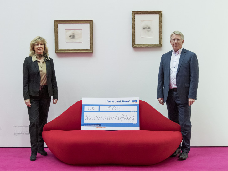 Otmar Böhmer, Geschäftsführer des Kunstmuseums Wolfsburg, nimmt eine Spende von Claudia Kayser, Leiterin der Direktion Wolfsburg der Volksbank BraWo, entgegen.