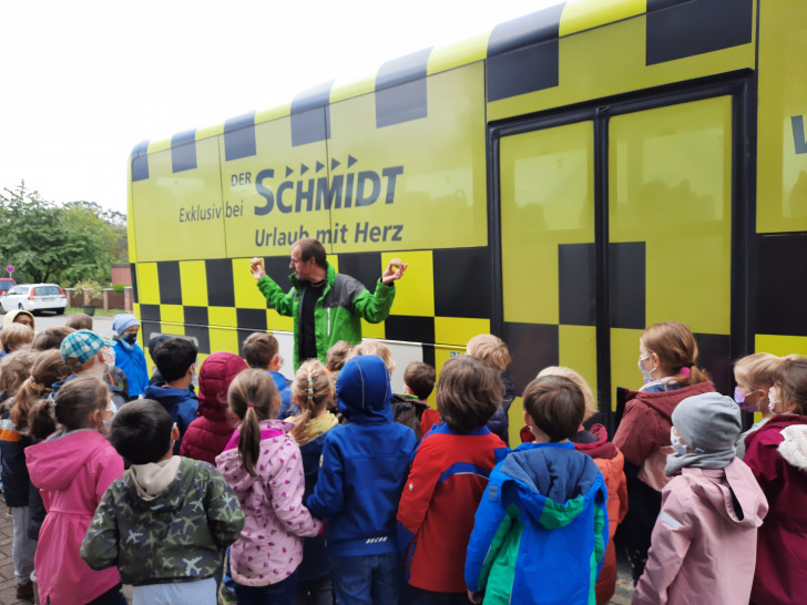 Hendrik Schmidt-Mühlen demonstriert den Erstklässlerinnen und Erstklässern die Kraft des rollenden Busses. 