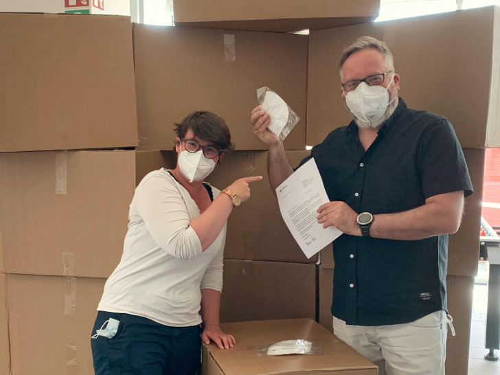 Von links: Katharina Hefenbrock und Thomas Stoch vom DRK nahmen 16 große Kartons mit jeweils 1.000 Masken entgegen.