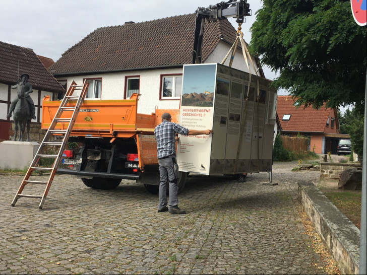 Ein Krahn hebt die mobile Ausstellungsbox an ihren neuen Standort am Hehlinger Roland.