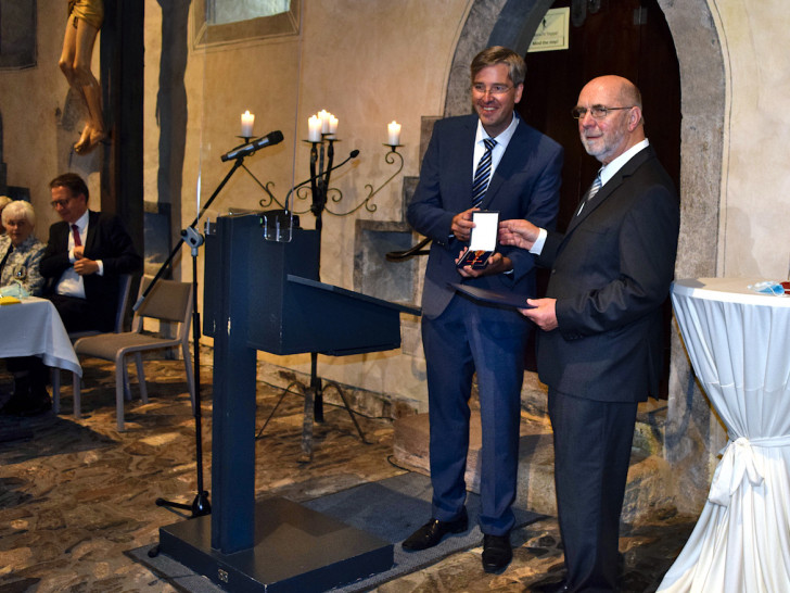 Oberbürgermeister Dr. Oliver Junk (links) überreicht Christian Rehse die Verleihungsurkunde und das Verdienstkreuz.