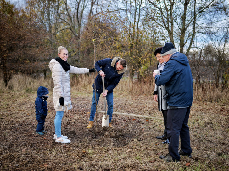 Eine Leinder Familie beim Pflanzen des Baumes für ihren Nachwuchs.