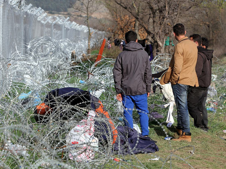 Flüchtlinge vor einem Grenzzaun (Archiv)