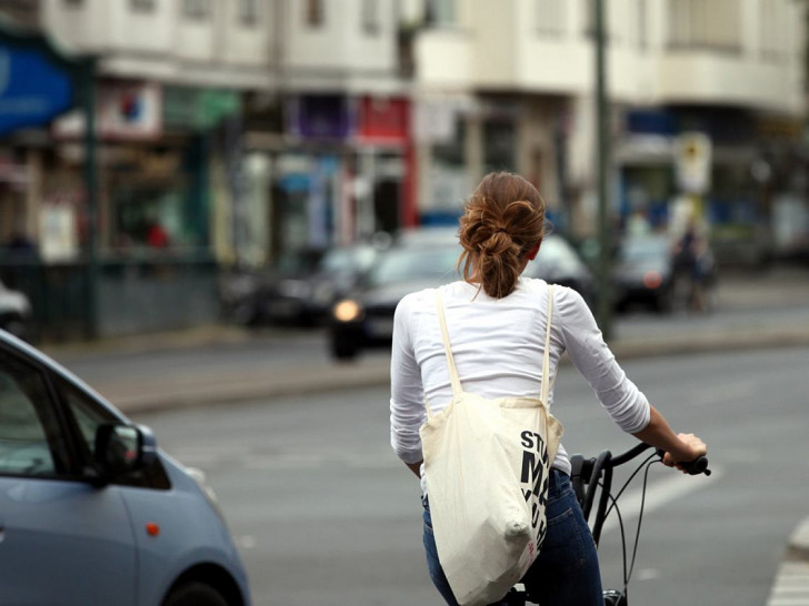 Junge Frau auf Fahrrad im Straßenverkehr (Archiv)
