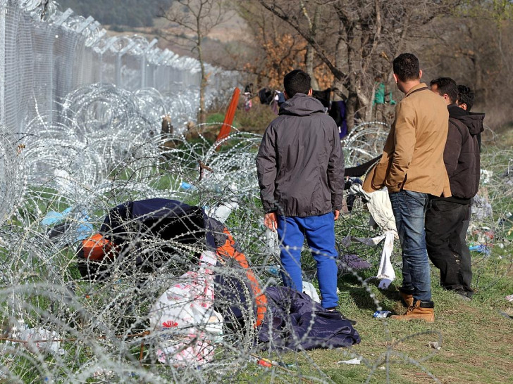 Flüchtlinge auf der Balkanroute vor einem Grenzzaun (Archiv)