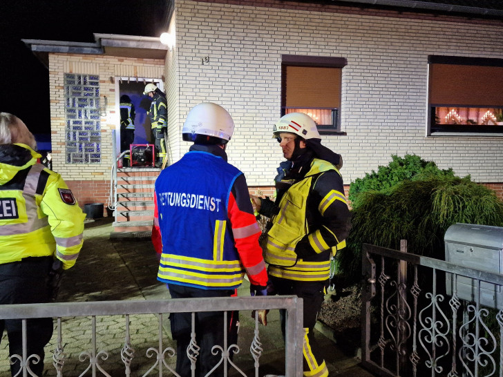 Einsatzleiter Marcel Tremer, Freiwillige Feuerwehr Abbesbüttel im Austausch mit dem Rettungsdienst; im Hintergrund wird das Gebäude von der Feuerwehr belüftet.