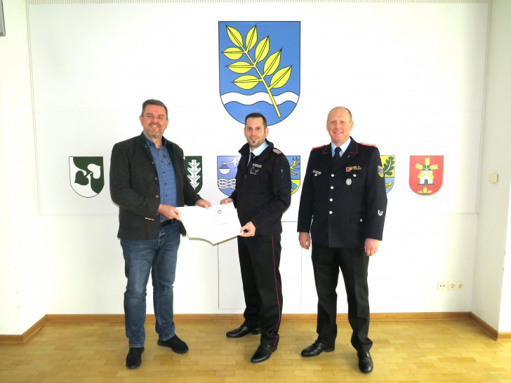 Gemeindebürgermeister Andreas Busch (li.) und Gemeindebrandmeister Simon Rebel (re.) gratulieren Jan Wehrstedt.