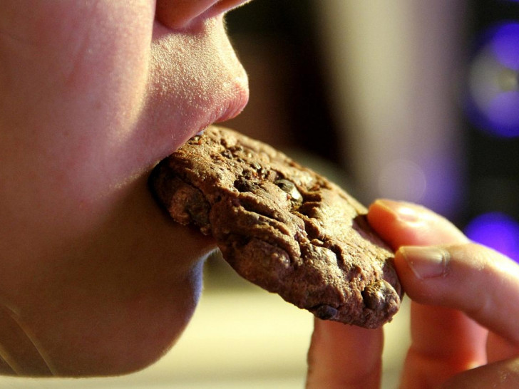 Junges Mädchen isst einen Schokoladenkeks (Archiv)