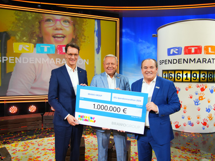 Jürgen Brinkmann, Vorstandsvorsitzender der Volksbank BRAWO (Bildmitte), überreicht während des RTL-Spendenmarathons im Fernsehstudio in Köln einen Spendenscheck über eine Million Euro an Wolfram Kons, Moderator und Gesamtleiter Charity bei RTL (rechts) im Beisein von NRW-Ministerpräsident Hendrik Wüst. 