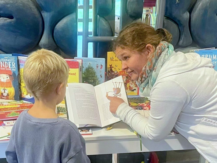 Sarina Nilsson zeigt Ben ein Buch von ihrem Büchertisch.