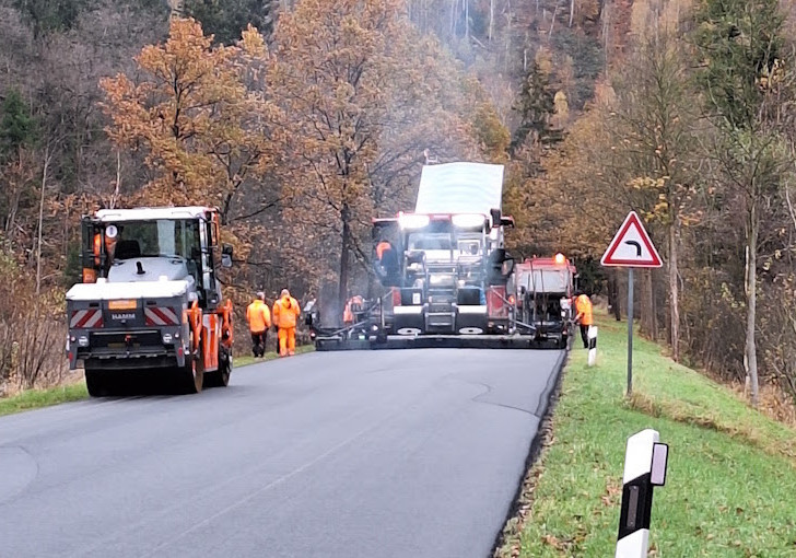 Auf der Landesstraße 515 wird die Asphaltdeckschicht auf ganzer Breite eingebaut.