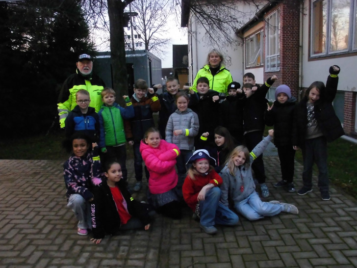 Klaus Seiffert von der Verkehrswacht und Silke Hitschfeld von der PI Wolfsburg-Helmstedt bei der Übergabe von Reflektionsmaterial an die Grundschulkinder.