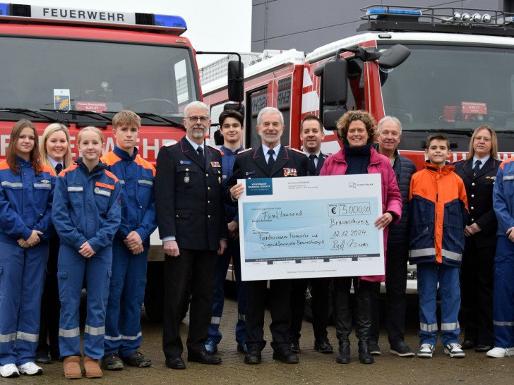 Nina Krumme, Volkswagen AG, übergibt den Spendenscheck in Anwesenheit von Mitgliedern der Jugendfeuerwehren Stöckheim, Watenbüttel, Völkenrode und Lamme an Harald Herr vom Förderverein Feuerwehr und Jugendfeuerwehr Braunschweig.